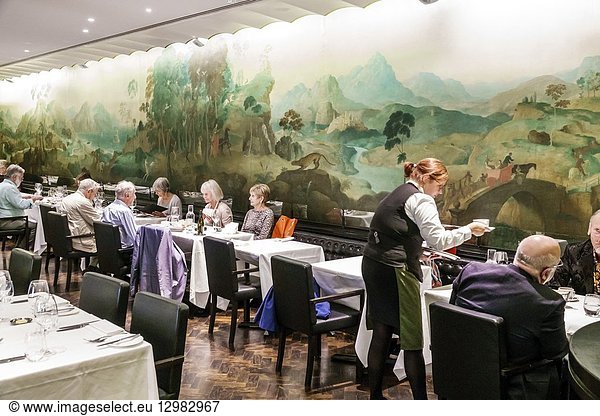 United Kingdom Great Britain England  London  Westminster  Millbank  Tate Britain art museum gallery  inside interior  Rex Whistler Restaurant  fine dining  wall mural  man  woman  tables  waitress  serving