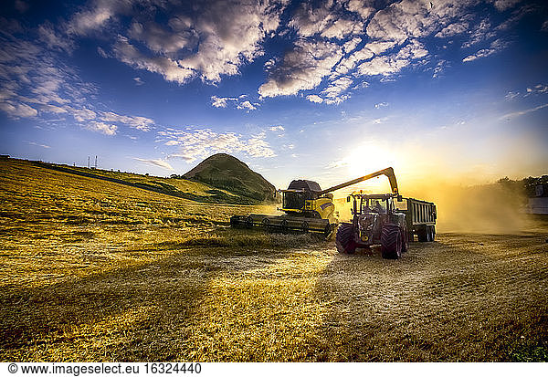United Kingdom  Scotland  East Lothian  North Berwick  Field  Combine harvester and tractor at sunset