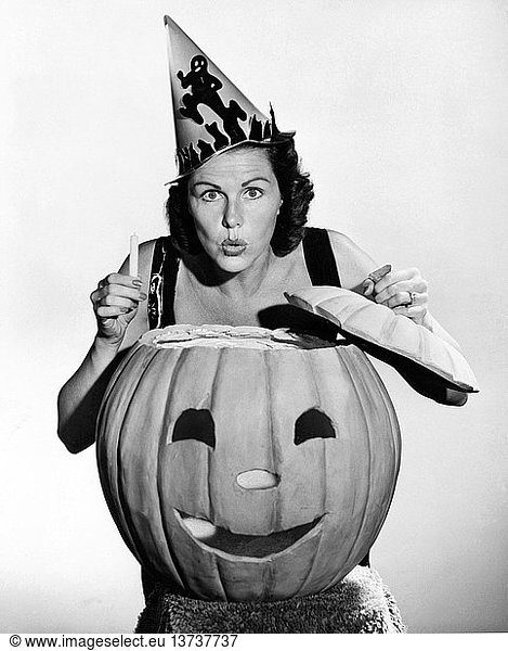United States: c. 1940 A woman looking scary with a pumpkin and a candle on Halloween.