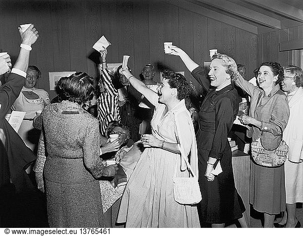 United States: c. 1955 A group of women at a gathering cheering and raising their glasses in a toast.