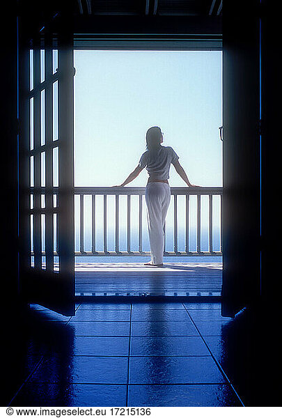 United States  United States Virgin Islands  St. John  Rear view of woman standing on balcony of holiday villa by sea