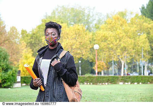 University female african student wearing protective face mask outside on campus. New normal in college.