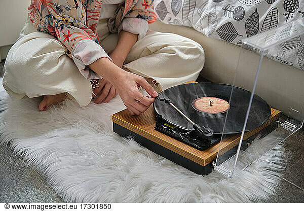 Unrecognizable girl playing a vinyl record on a turntable