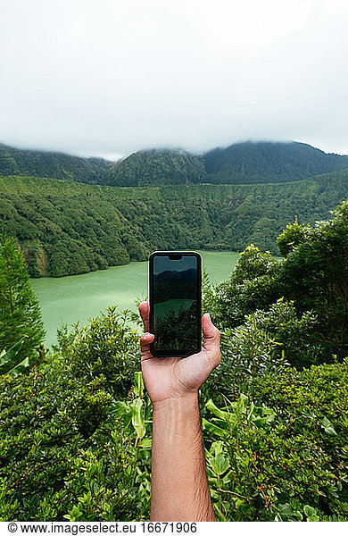 Unrecognizable person holding a cellphone in the mountains