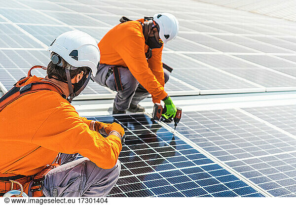Unrecognizable solar panel technicians teamworking in Spanish factory
