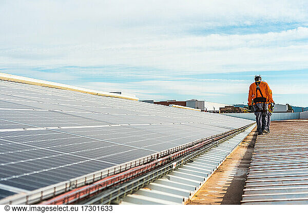 Unrecognizable solar panel technicians walking in Spanish installation