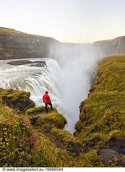 Unrecognizable traveler standing near waterfall