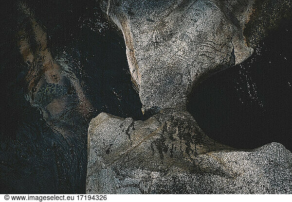 Untergetauchte weibliche Figur schwimmt durch schwarzes Wasser und Stein
