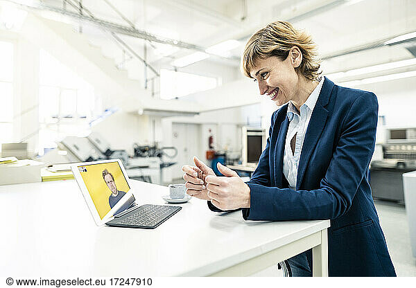 Unternehmerin diskutiert mit einem Kollegen per Videoanruf auf einem digitalen Tablet in einem Workshop