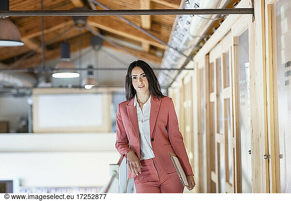 Unternehmerin lehnt am Geländer im Büroflur