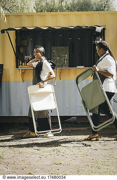 Unternehmerinnen mit Stühlen gehen an einem Imbisswagen vorbei