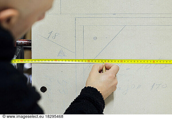 Upholsterer using measuring tape in workshop