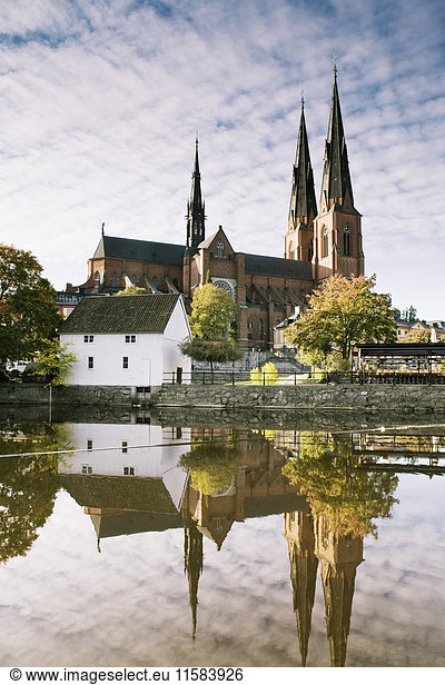 Uppsala Cathedral reflecting in River Fyris against sky