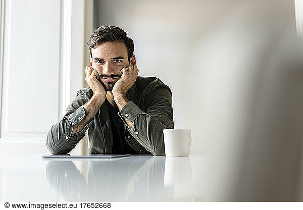 Upset man with tablet PC sitting on table at home