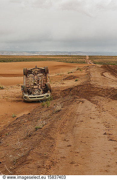 upside down car that has flipped on a muddy dirt road in utah desert
