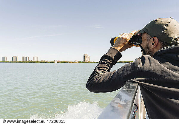 USA  Florida  Sanibel  Mann betrachtet das Meer durch ein Fernglas