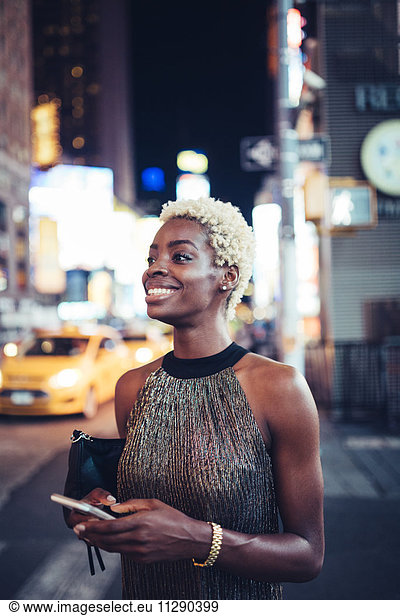 USA  New York City  smiling young woman waiting on Times Square at night