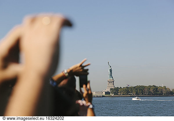 USA  New York City  Touristen beim Fotografieren der Freiheitsstatue