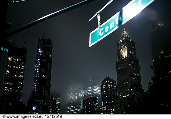 USA  New York  New York City  Straßennamensschild  das nachts an beleuchteten Wolkenkratzern hängt