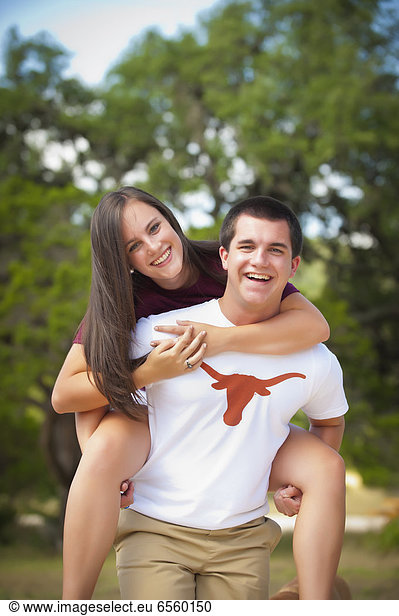USA  Texas  Teenage boy giving piggyback to teenage girl  smiling  portrait