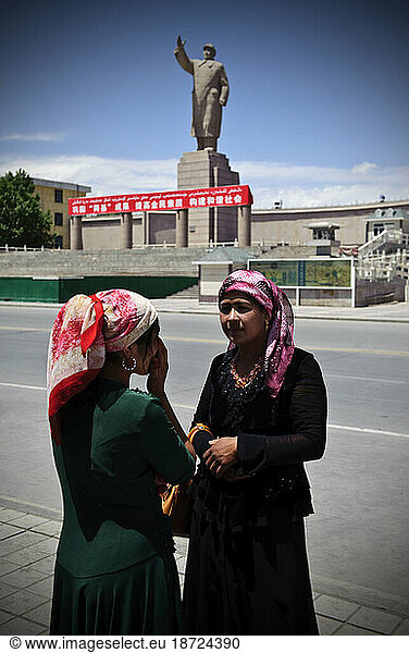 Uyghur women in the main city square of Kashgar  Xinjang  China with the Mao Zedong (Tse-tung) statue in the background.