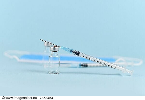 Vaccine concept with syringe  vial and face mask in blurry blue background