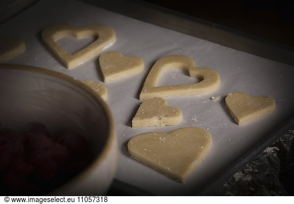 Valentine's Day baking,  high angle view of heart shaped biscuits on a baking tray.