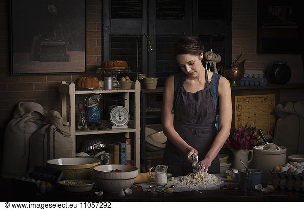 Valentine's Day baking,  young woman standing in a kitchen,  preparing dough for biscuits.