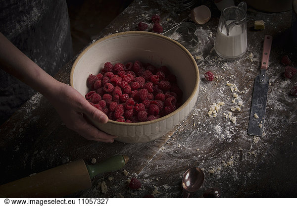 Valentine's Day baking. A bowl of fresh raspberries on a floury table.