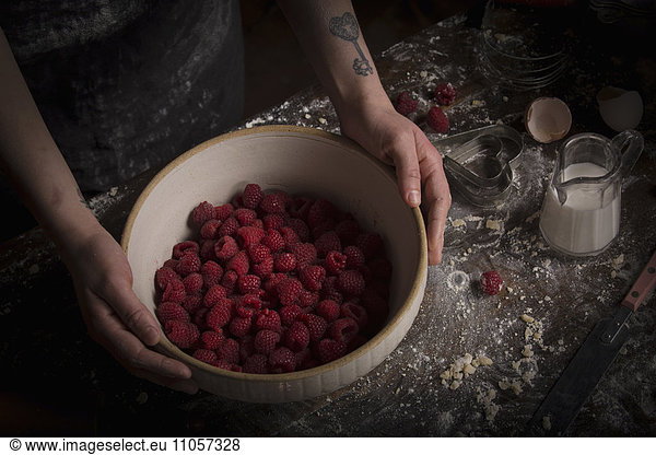 Valentine's Day baking. A woman preparing raspberries in a bowl.