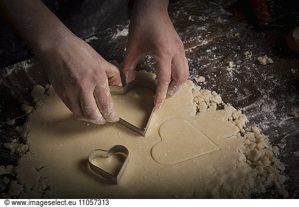 Valentine's Day baking  woman cutting out heart shaped biscuits from dough.