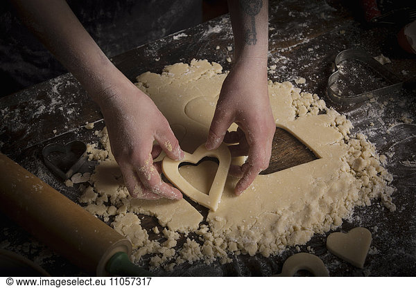 Valentine's Day baking  woman cutting out heart shaped biscuits from dough.