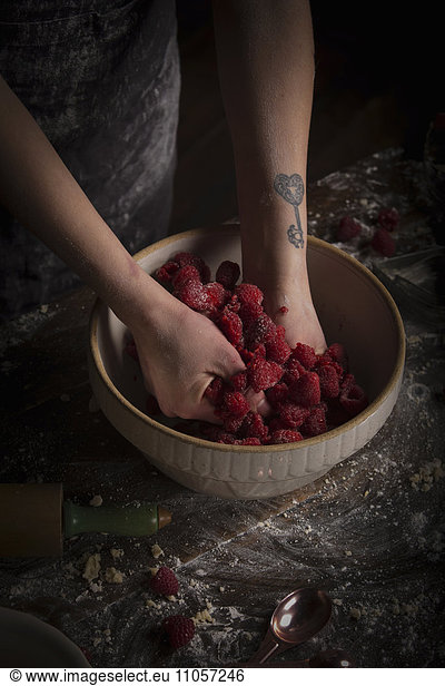 Valentine's Day baking  woman preparing fresh raspberries in a bowl.