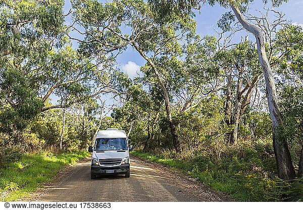 Van driving along dirt stretch of Great Ocean Road in summer