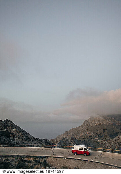 Van moving on road overlooking mountains against sky