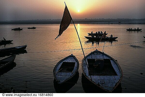 Varanasi  Uttar Pradesh  Indien  Asien - Tagesanbruch mit Sonnenaufgang über hölzernen Ruderbooten an einem Ghat am Ufer des heiligen Flusses Ganges.