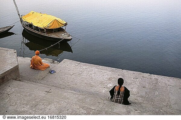 Varanasi  Uttar Pradesh  Indien  Asien - Zwei Menschen sitzen an einem Ghat am Ufer des heiligen Ganges und schauen auf den Fluss.