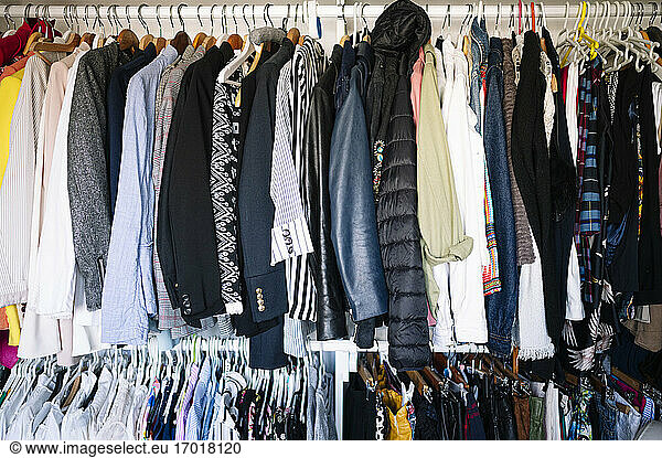 Variation of clothes hanging on rack in wardrobe at apartment