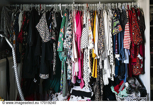 Variation of womenswear hanging on clothes rack in wardrobe at apartment