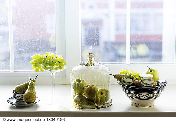 Various fruits in containers on window sill