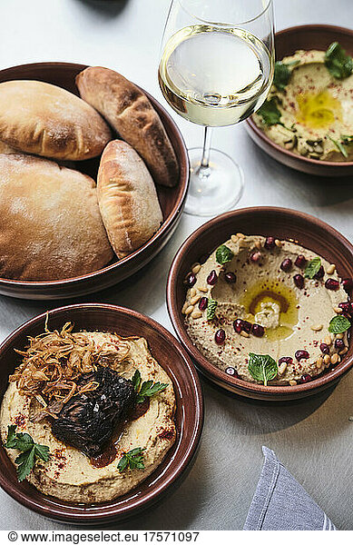 Various types of gourmet hummus on a full table with bread.