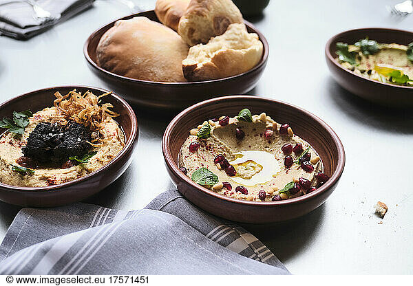 Various types of gourmet hummus on a full table with bread.