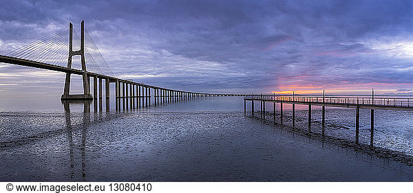 Vasco-da-Gama-Brücke über den Tejo gegen bewölkten Himmel bei Sonnenuntergang