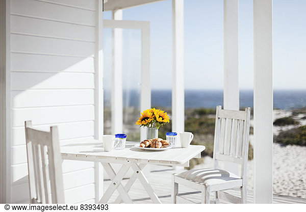 Vase of flowers  coffee and pastries on patio table overlooking ocean