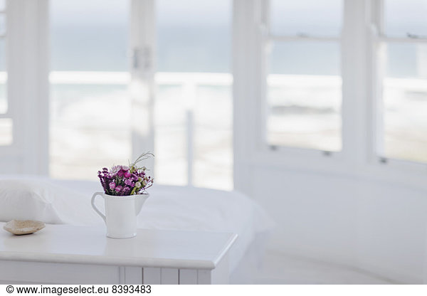 Vase of flowers on desk in bedroom overlooking ocean