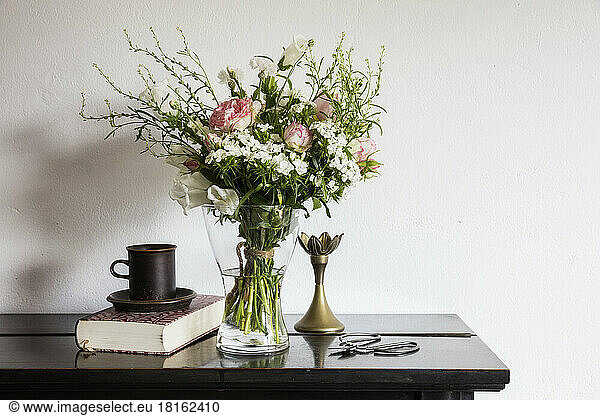 Vase with freshly cut flowers standing on shelf