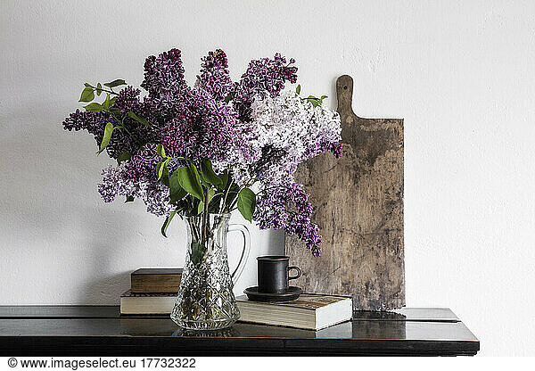 Vase with freshly picked lilacs (Syringa vulgaris) standing on shelf