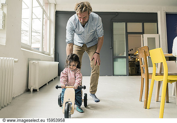 Vater beobachtet Tochter mit Balance-Fahrrad
