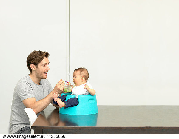 Vater füttert Baby Junge im Kindersitz
