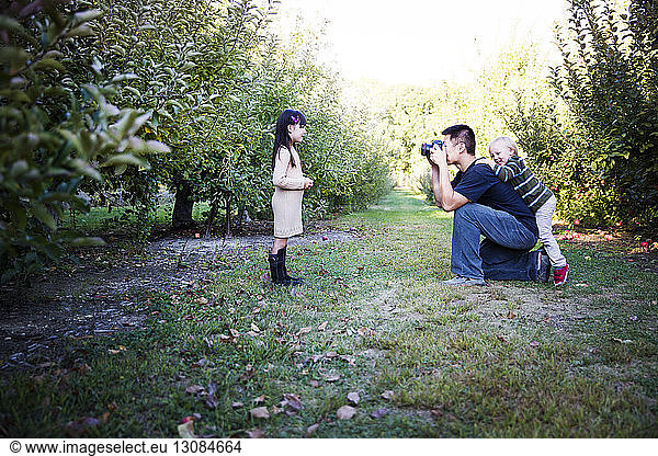 Vater fotografiert Tochter im Apfelgarten